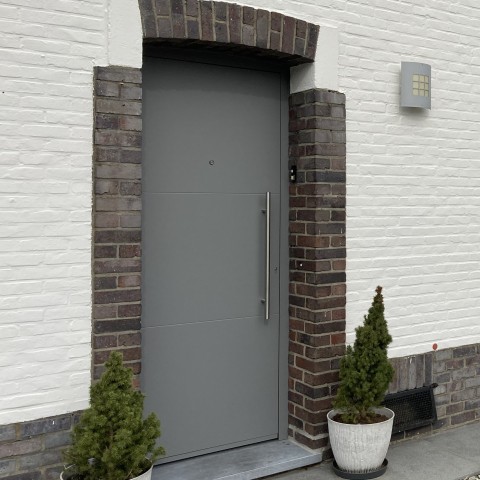 Lichtgrijze minimalistische vlakke alu voordeur in klassieke woning in Hasselt