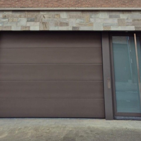 Grijze inkomdeur gekoppeld aan nieuwe garagepoort geplaatst door Winfera
